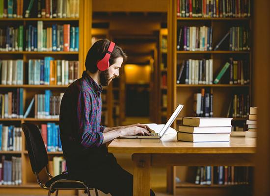 澳门新普京注册 student working on homework in the library.